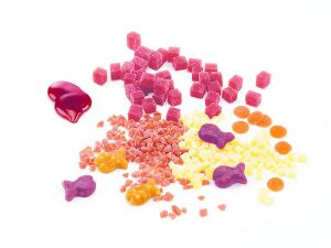 Fruit granules of different cut sizes mixed with fish-shaped fruit gums, fruit drops and fruit paste.