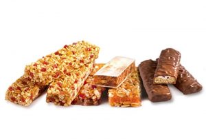 Cereal bars, fruit bars and chocolate bars stacked next to each other.