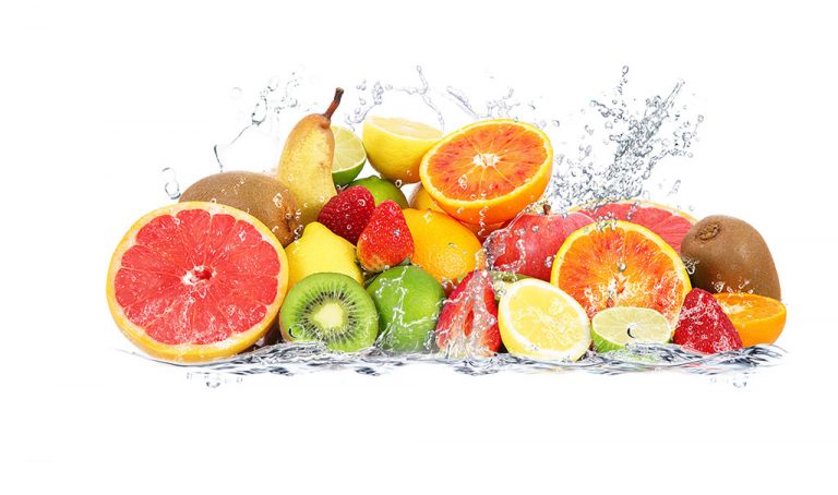 Fruta fresca parcialmente cortada colocada en un círculo de gotas de agua.
