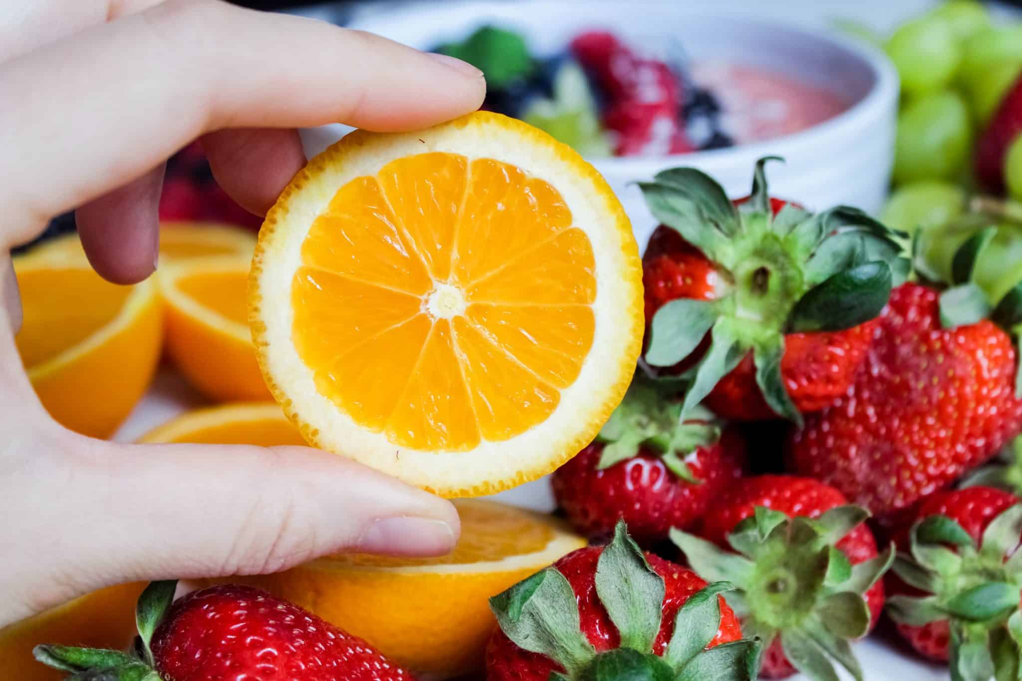 Fruity orange slice next to several strawberries.