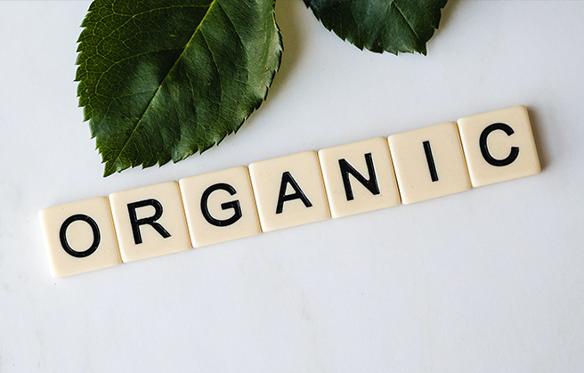 Piezas de Scrabble deletreando la palabra "orgánico" sobre una mesa.