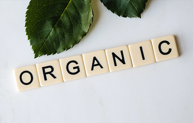 Scrabble pieces spelling out the word "organic" on a table.