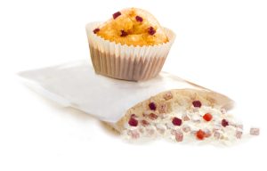 An opened baking mix with pieces of fruit in it. On it is a baked muffin with fruit pieces.