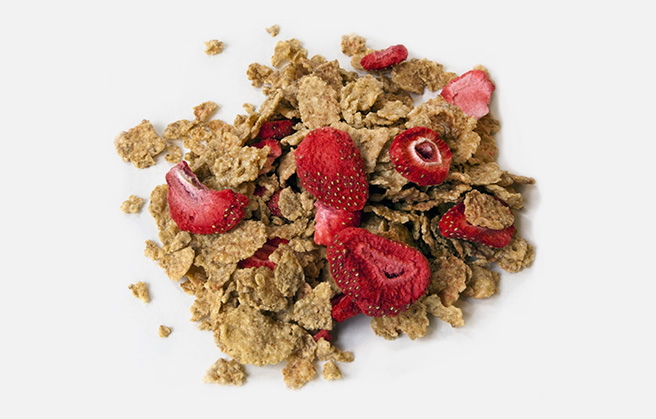 Cornflakes mixed with freeze-dried strawberry pieces.